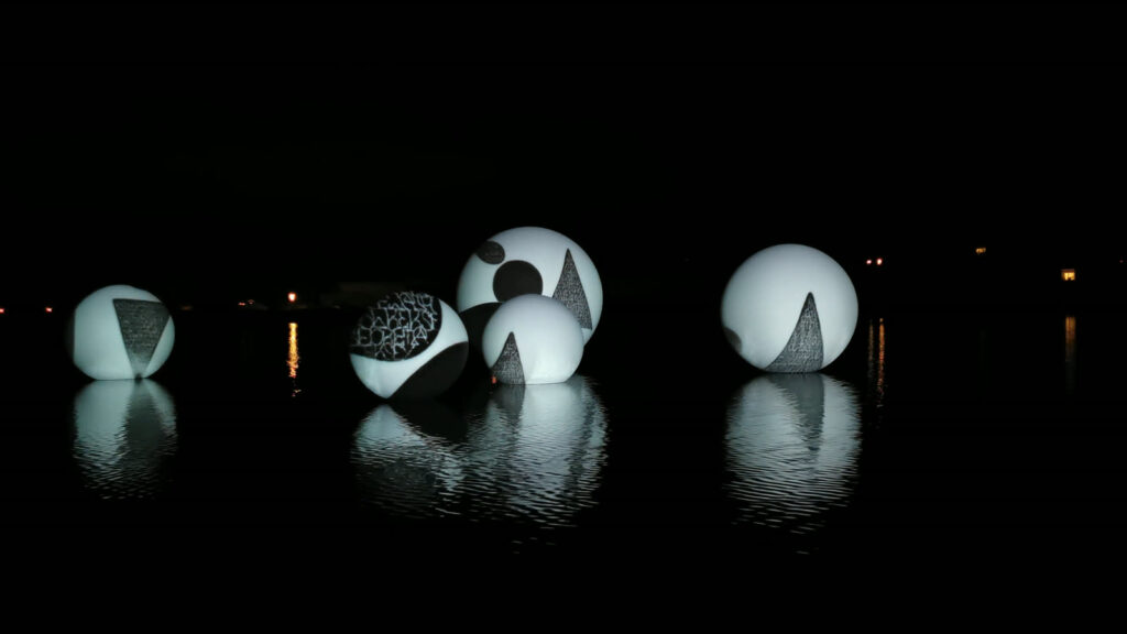 Sphères éclairées sur l’eau face aux lumières du port, Étel